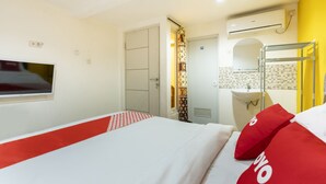 A hotel room with a bed, a TV, a wardrobe, a bathroom with a sink and mirror, and a window. - OYO Life 3782 Gunung Anyar (Surabaya)
