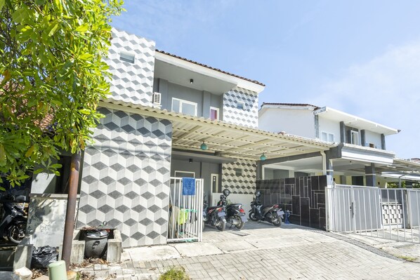 Uma casa moderna de dois andares com fachada geométrica, entrada coberta e portão.