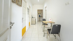 A hallway with a table and chairs, a sink, and a door. - OYO Life 3782 Gunung Anyar (Surabaya)