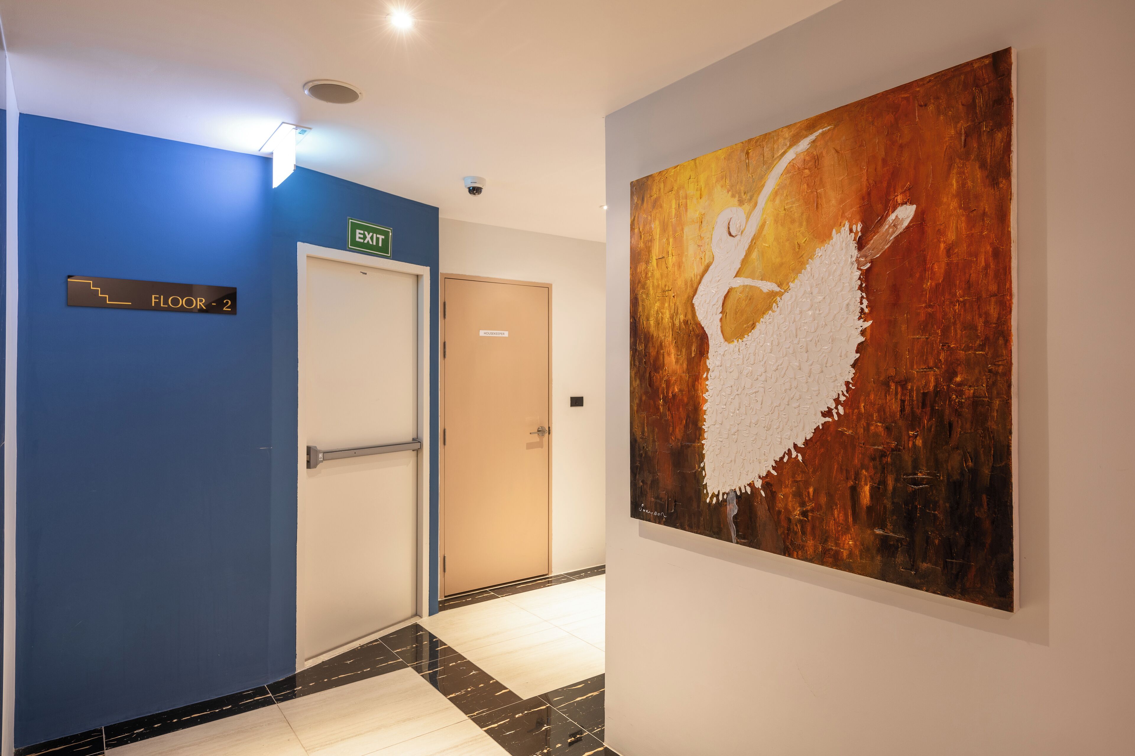 A hallway with a blue wall, a sign indicating 'Floor 2', and an exit door.