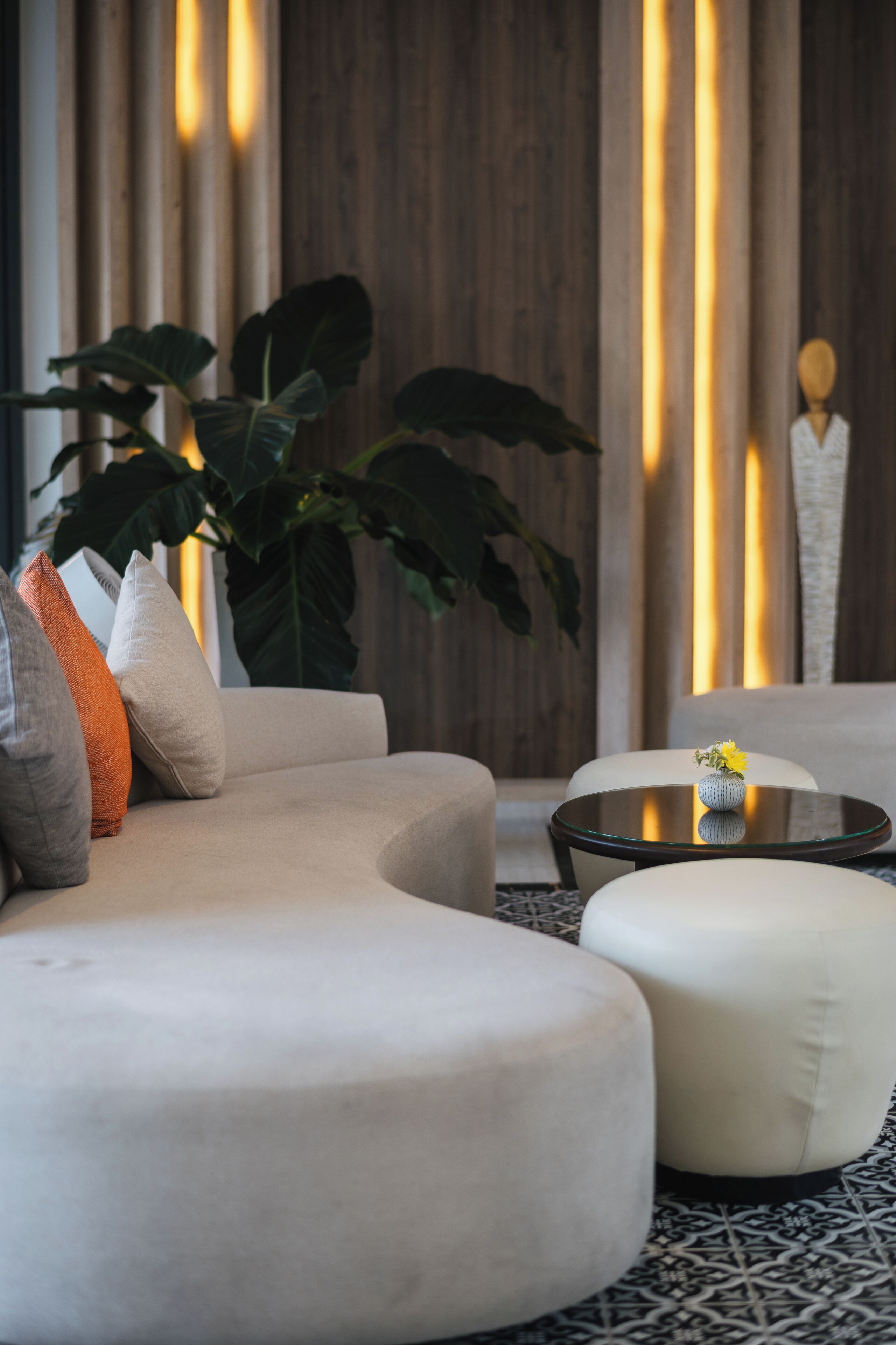 Una sala de estar moderna con un sofá, un reposapiés y una mesa de centro de vidrio.