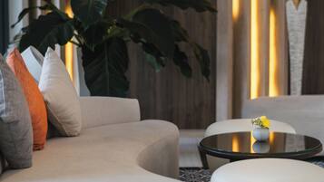 Una sala de estar moderna con un sofá, un reposapiés y una mesa de centro de vidrio.