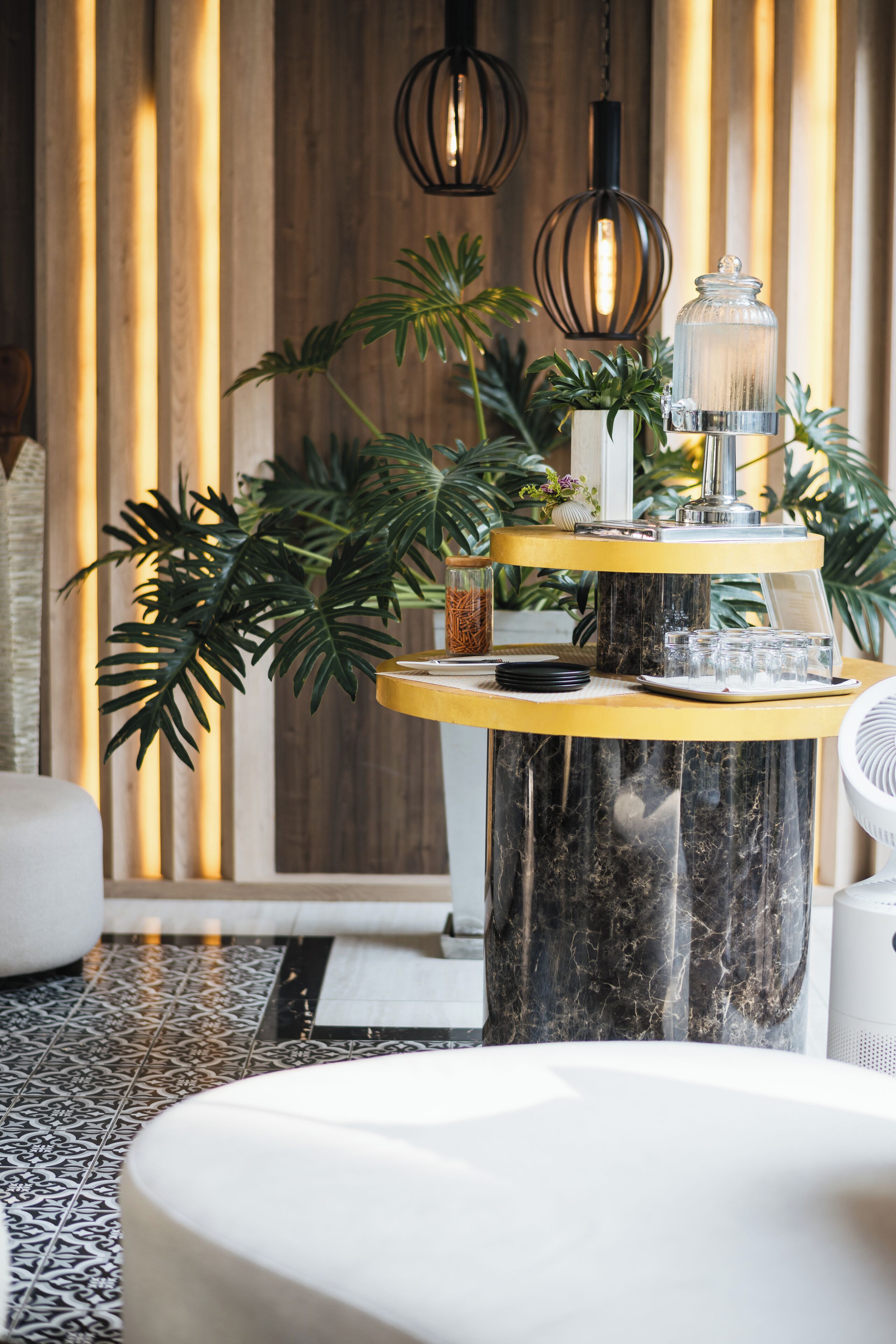 A modern interior with a marble table, potted plants, and hanging lights.