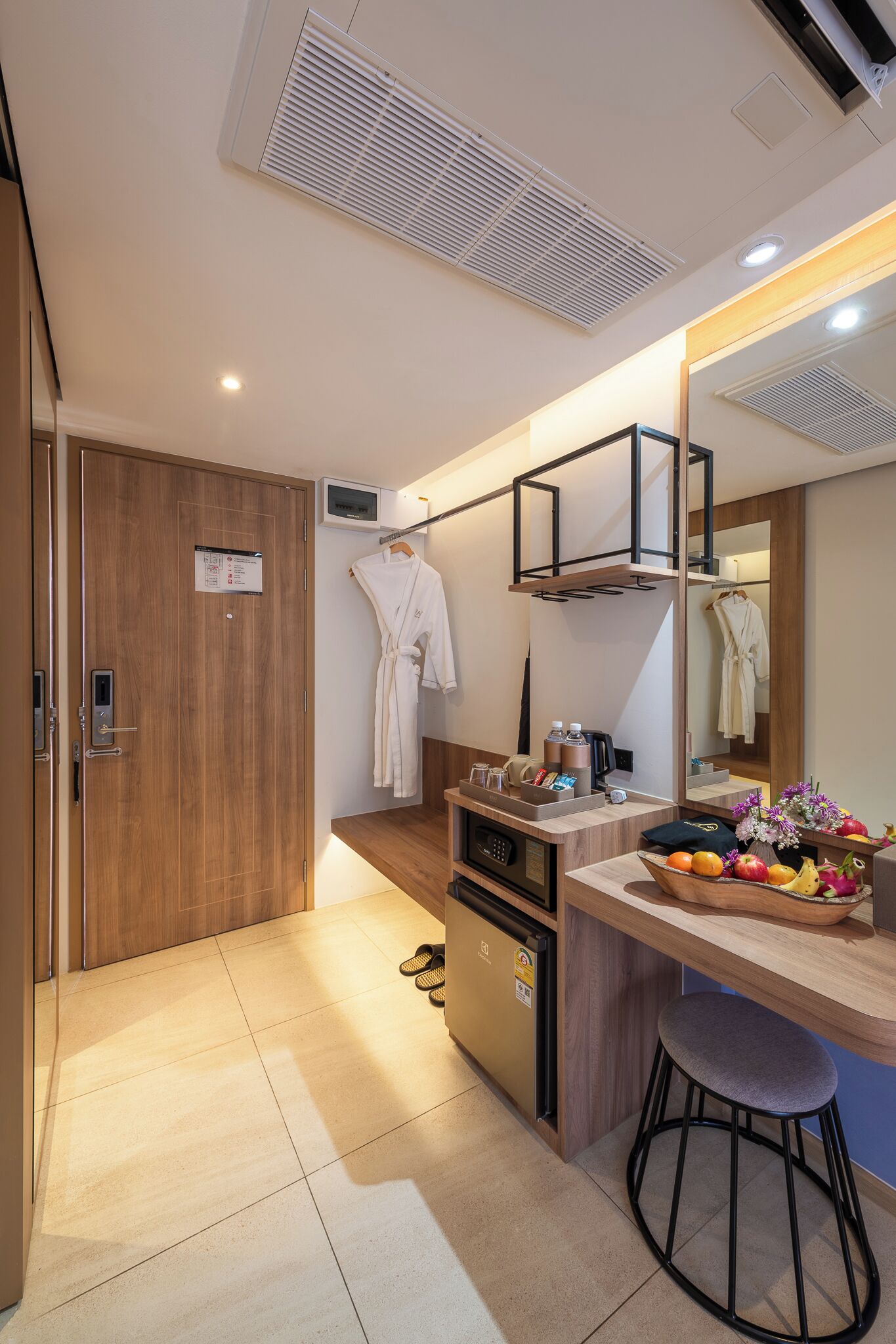 Un baño moderno con puerta de madera, un perchero, un espejo, un lavabo y un taburete.