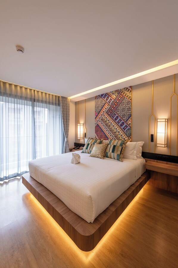 A modern hotel room with a large bed, wooden platform, and patterned wall art. - Stay Collection Chiangmai (Chiang Mai)