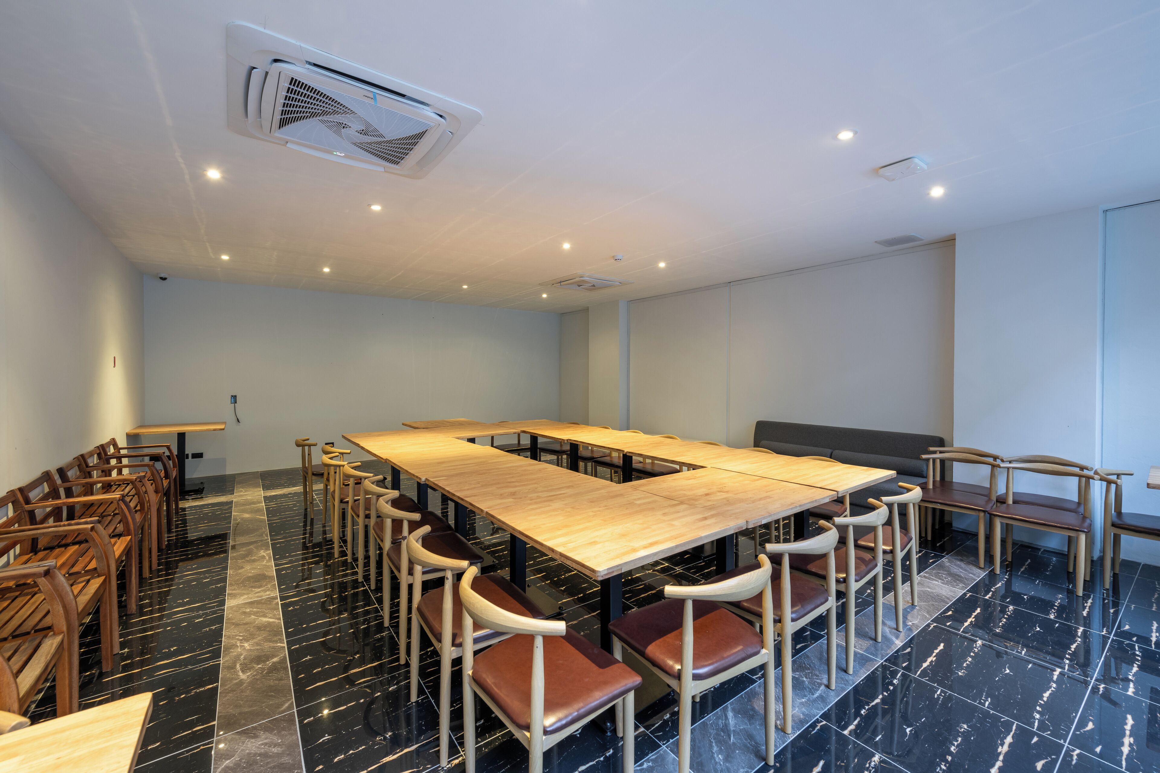 Uma sala de conferências com uma mesa comprida, várias cadeiras e um chão de mármore preto.