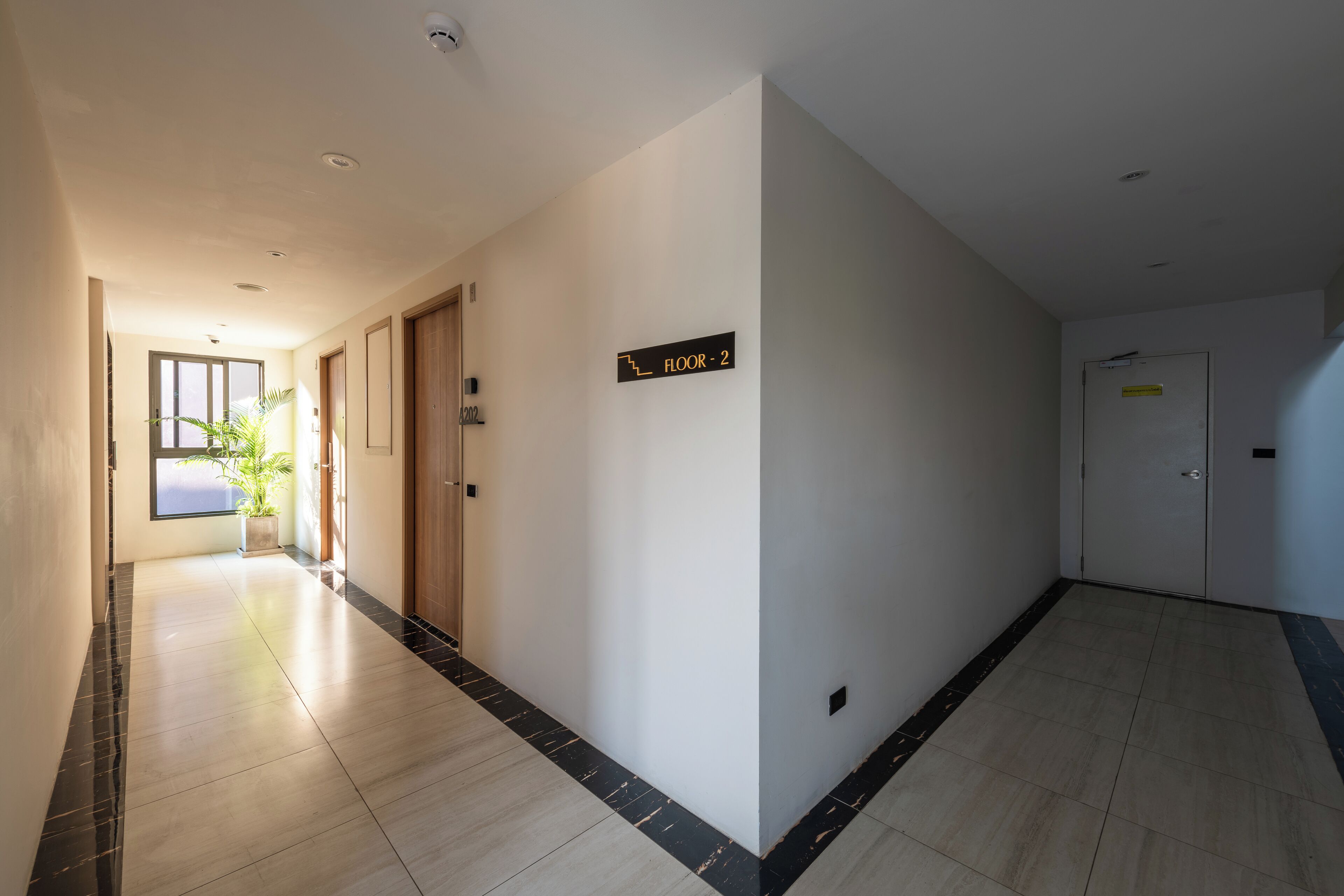 A hallway with a sign indicating 'Floor 2', a potted plant, and a door with a handle.