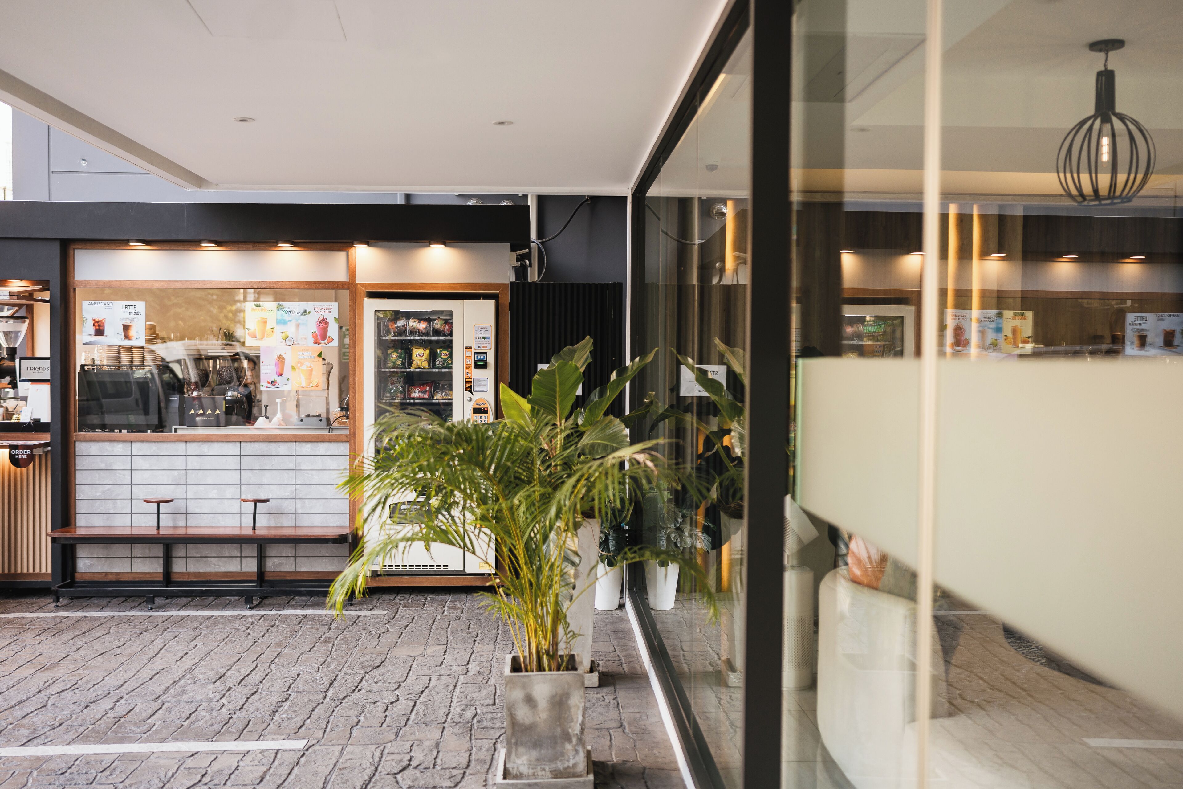 Un café moderno con suelo de ladrillo, zona de estar y plantas en macetas.