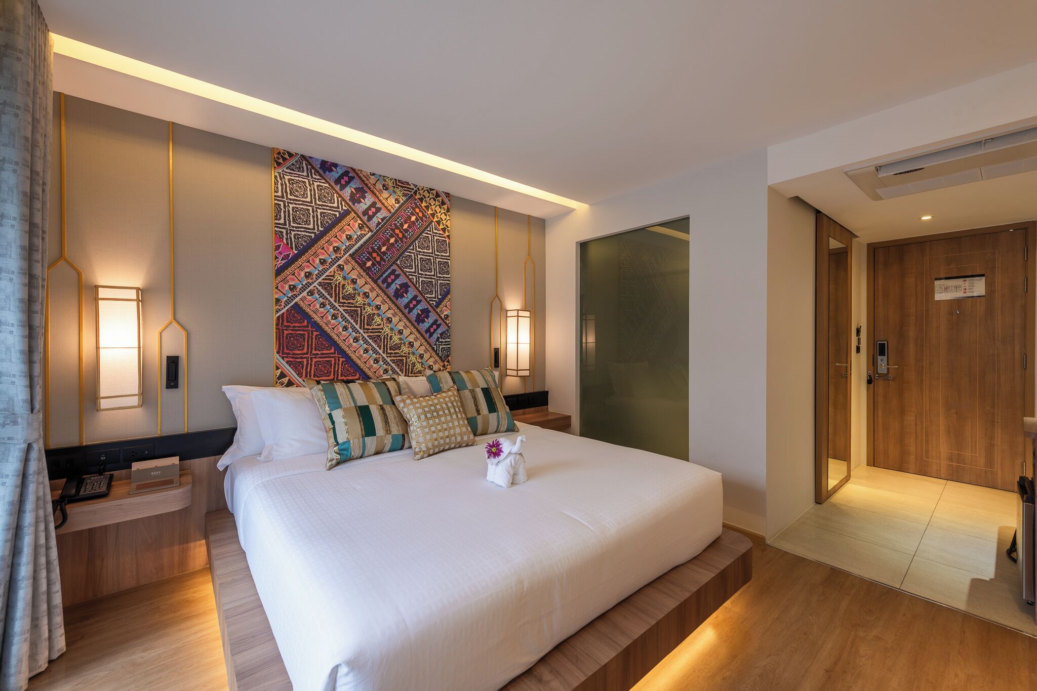 Een moderne hotelkamer met een groot bed, een behangwand en een houten deur.