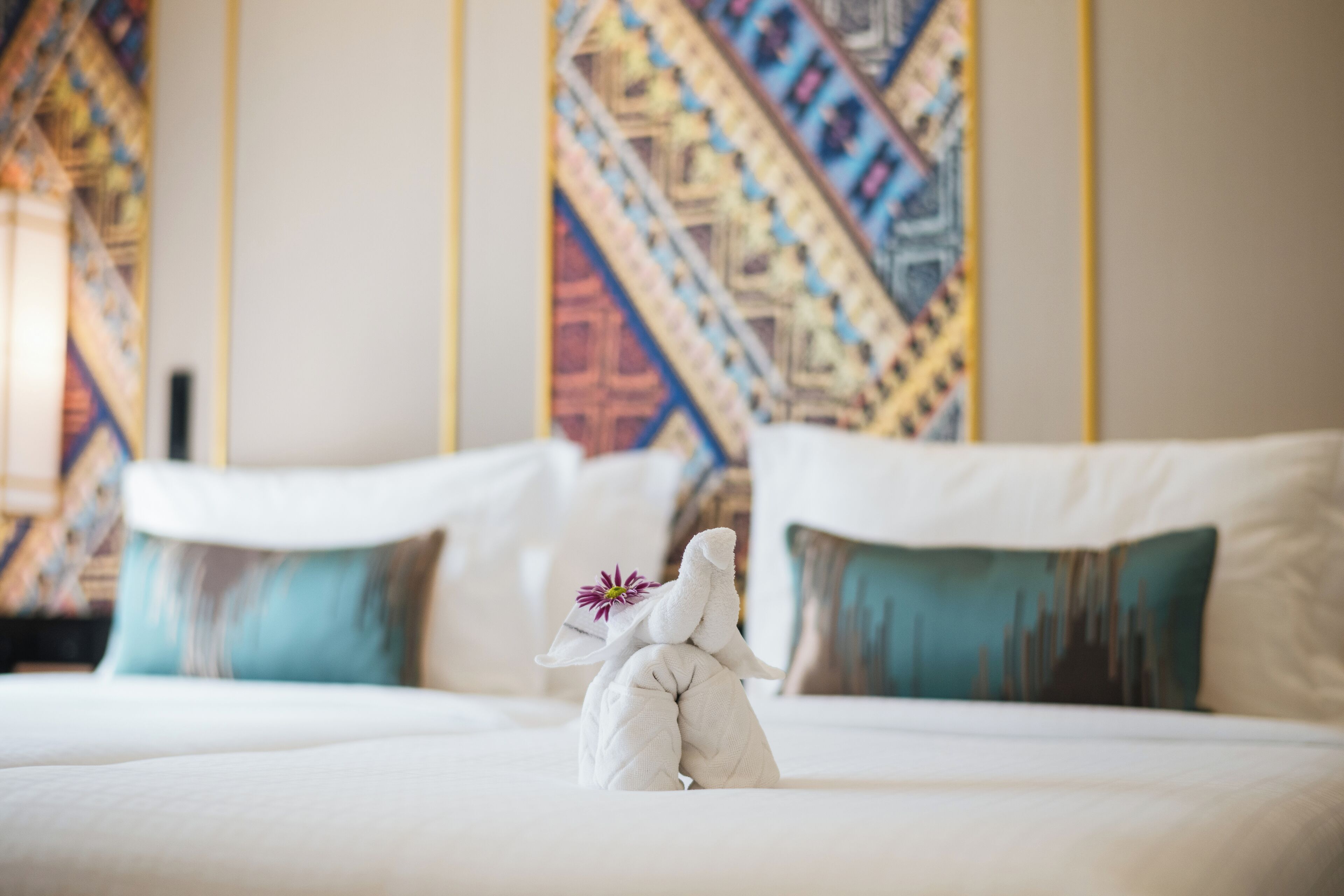 A neatly made bed with a decorative pillow and a towel sculpture.