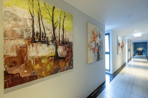 Un pasillo con pinturas abstractas en las paredes y vista a otra habitación.