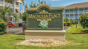 A sign for Magnolia Place with a decorative emblem. - Myrtlewood Resorts Serene Getaway Unit 105 (Myrtle Beach)