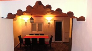 Comedor con una mesa, sillas, dos luces en la pared y una puerta.