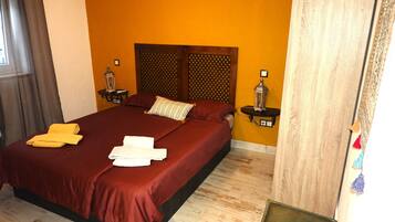 A hotel room with a large bed, two bedside tables with lamps, a wooden headboard, and a yellow wall.