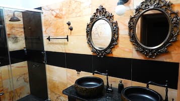 A bathroom with two sinks, a shower, and two ornate mirrors.