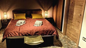 Un dormitorio acogedor con una cama grande, dos lámparas de noche y un banco al pie de la cama.