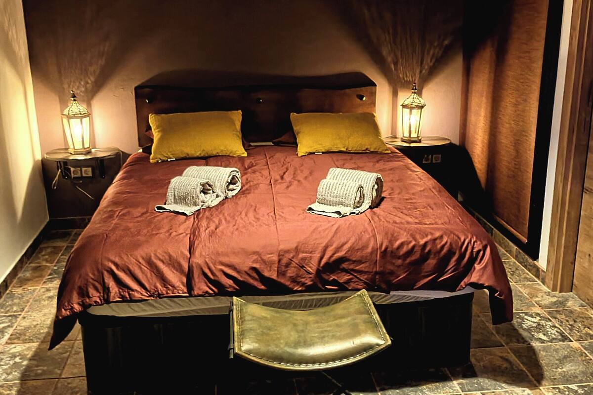 A cozy bedroom with a large bed, two bedside lamps, and a bench at the foot of the bed.
