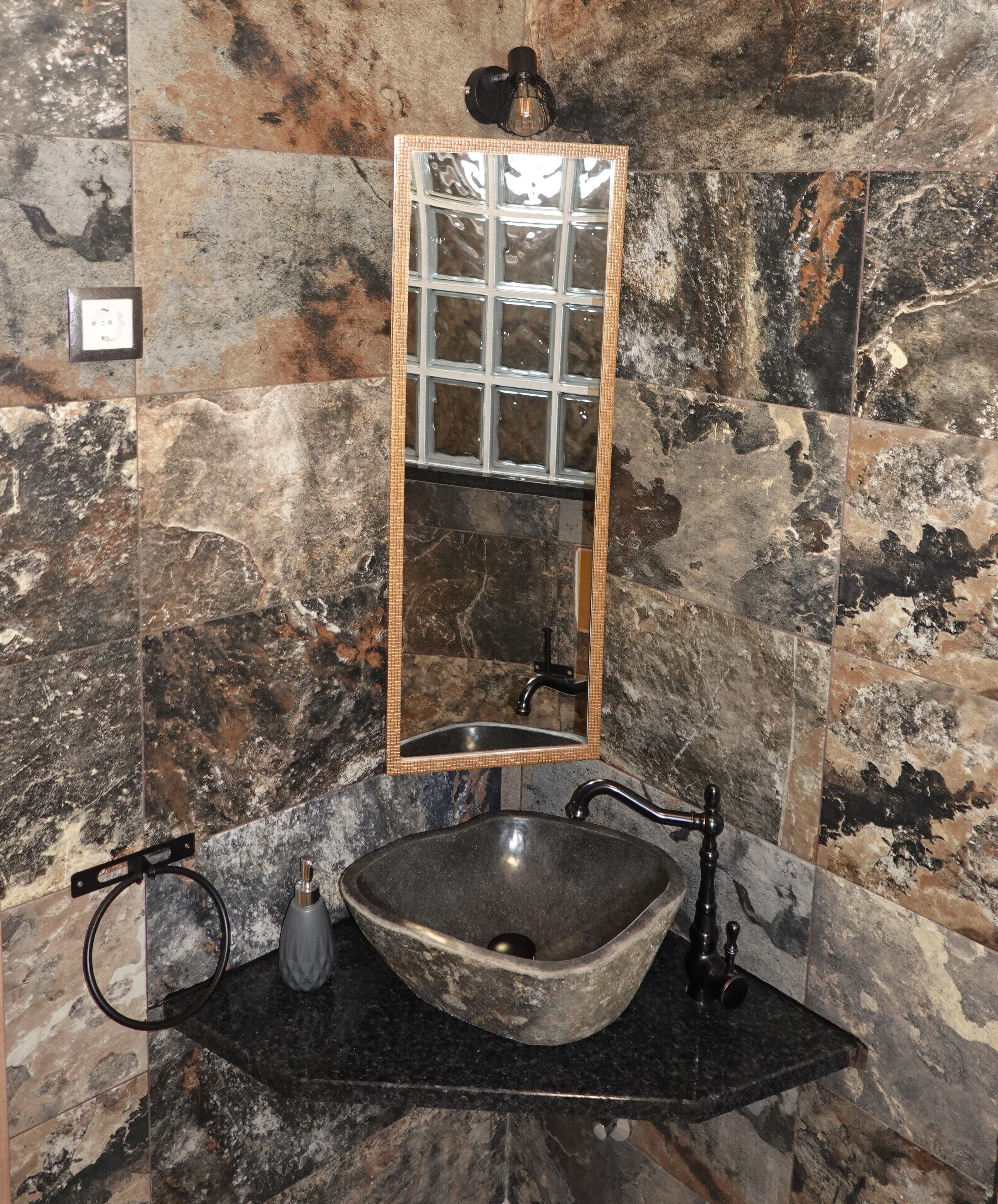 A bathroom with a stone sink, a mirror, and a towel rack.