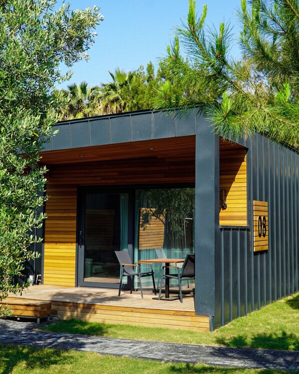 A modern building with a wooden deck, outdoor seating, and a large window. - La Vida Hotel (Datça)