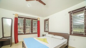 Une chambre à coucher avec un lit, une table de chevet, un miroir et des fenêtres avec des rideaux.