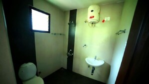 Une petite salle de bain simple, équipée de toilettes, d’un lavabo et d’une fenêtre.