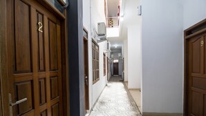 Un corridoio stretto con porte in legno, piastrelle decorative a pavimento e un piccolo balcone con ringhiera ornamentale.