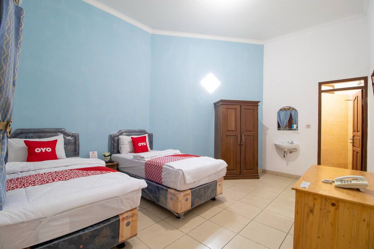 Een kamer met twee bedden, een houten bureau, een telefoon en een spiegel.