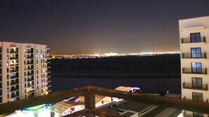 Vista notturna di una città costiera con edifici illuminati e uno specchio d'acqua.
