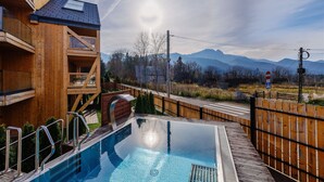 Ein Holzhaus mit Pool, einer Holzterrasse und Bergblick.