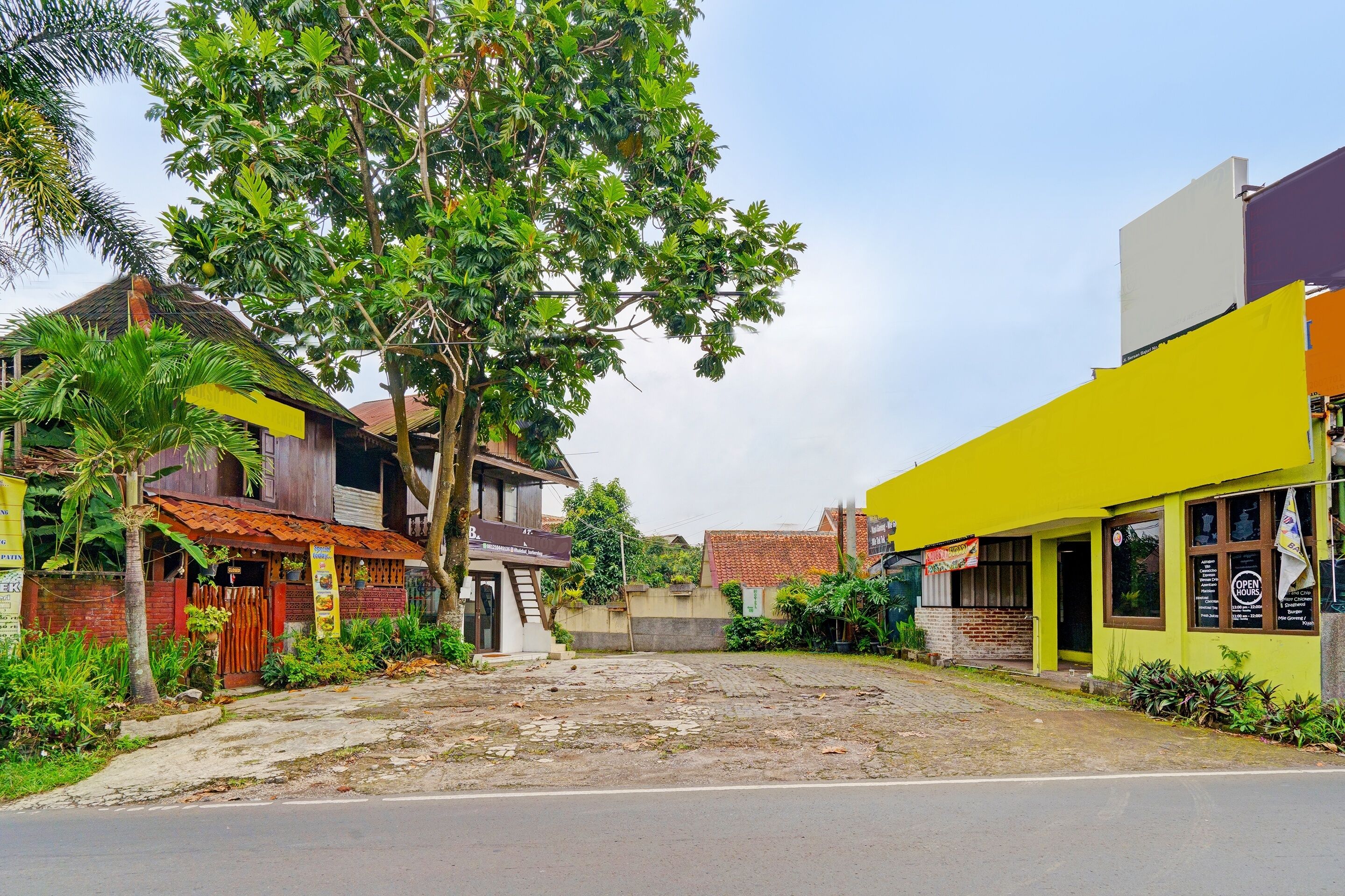 A street view with a building that has a yellow facade and a sign indicating it is open for business.