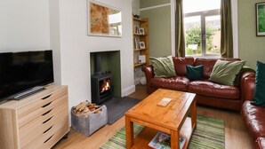 Una sala de estar acogedora con chimenea, sofá de cuero, mesa de centro de madera y televisor.