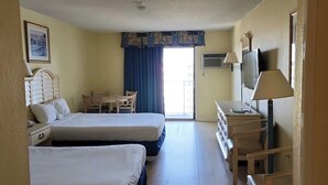A hotel room with two beds, a desk, a chair, a television, and a window with curtains.