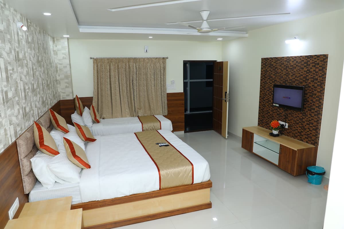 A hotel room with a large bed, a TV mounted on the wall, and a wooden cabinet.