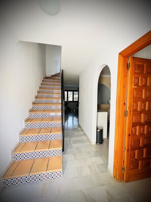 Un escalier recouvert de carreaux décorés mène à un couloir.