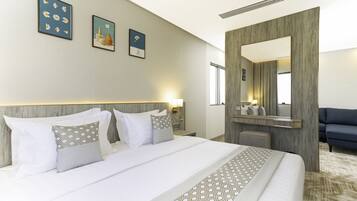 A hotel room with a large bed, a wooden headboard, a mirror, and three wall-mounted artworks.