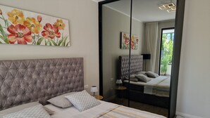 Un dormitorio con cabecera capitonada, cama con ropa de cama a rayas y dos cuadros en la pared.
