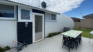 Una casa móvil con terraza, antena parabólica y una mesa con sillas.