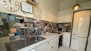 Una cocina moderna con encimera blanca, pileta de acero inoxidable y refrigerador blanco.