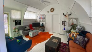 Un acogedor salón tipo loft con techo alto, un ventanal grande y una alfombra de cuero de vaca.