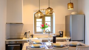 Cocina moderna con comedor para cuatro, que incluye electrodomésticos de acero inoxidable, un amplio ventanal con flores e iluminación colgante.