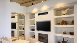 Una sala de estar moderna con televisión de pantalla plana, estanterías empotradas, chimenea y un rincón de descanso acogedor.