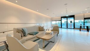 Un hall d’entrée moderne et bien éclairé, avec un canapé, des fauteuils et une table basse.