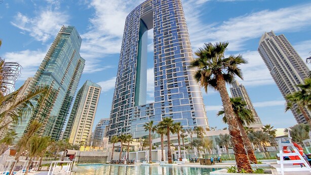 A high-rise hotel with a modern design, featuring a large central atrium and multiple balconies. - bnbme | Address Beach Resort | 1 BDR (Dubai)