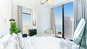 A modern hotel room with a large bed, a view of the city, a plant, and a mirror. - bnbme | Address Beach Resort | 1 BDR (Dubai)