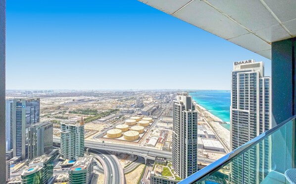 Un edificio alto con vistas a una ciudad costera, que incluye una playa y zonas industriales.