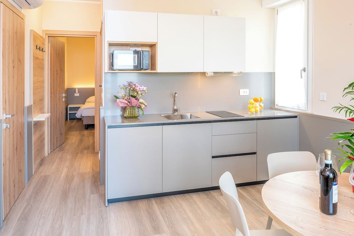A modern kitchen with a microwave, sink, and a dining area with a table and chairs.