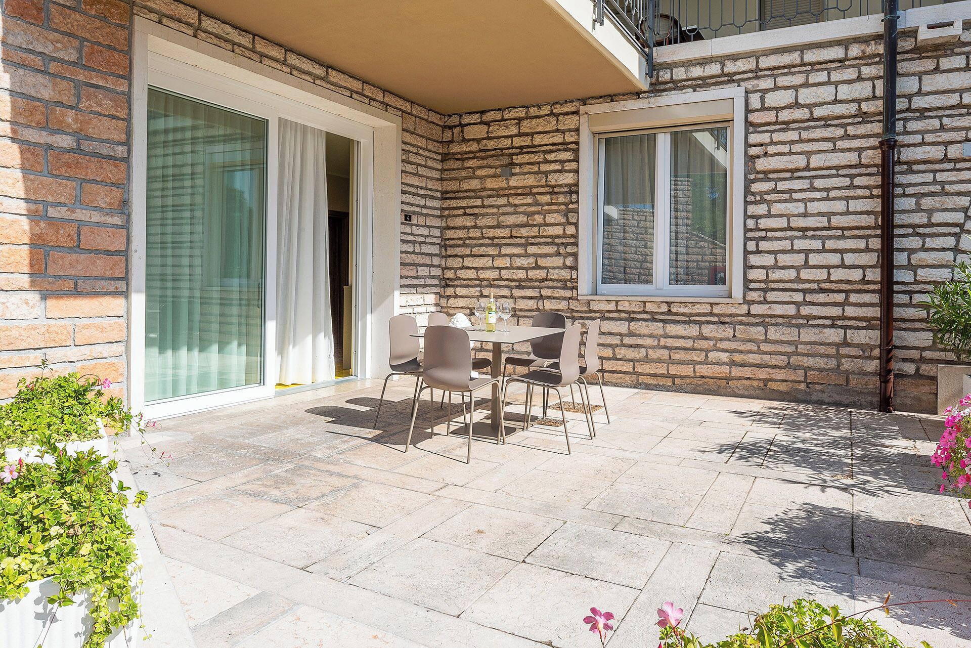 Un patio con tavolo e sedie, una porta scorrevole in vetro e un muro in mattoni.