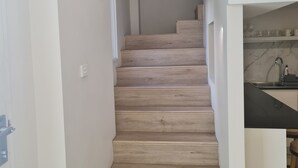Un escalier menant à un espace cuisine doté d’un plan de travail en marbre et d’un évier.