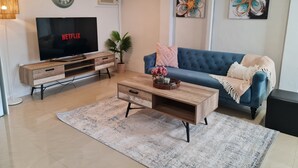 Un salon moderne comprenant un téléviseur, un canapé, une table basse et des objets de décoration.