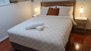 Un lit bien fait, avec une couette à carreaux, deux lampes de chevet et une tête de lit en bois.